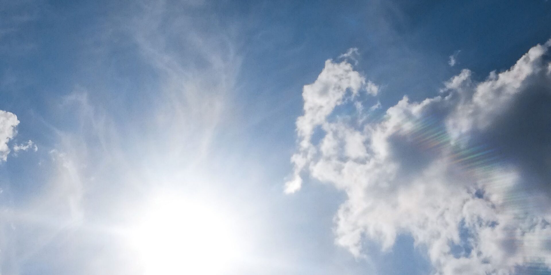 bright-august-sun Bright summer sun shining through scattered clouds in a blue sky, representing the heat and dry conditions that stress trees in August.
